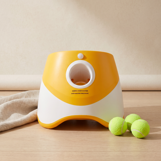 Automatic tennis ball launcher for dogs in orange with three tennis balls